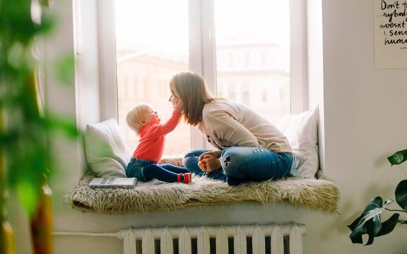 Mother and toddler sitting on window bench